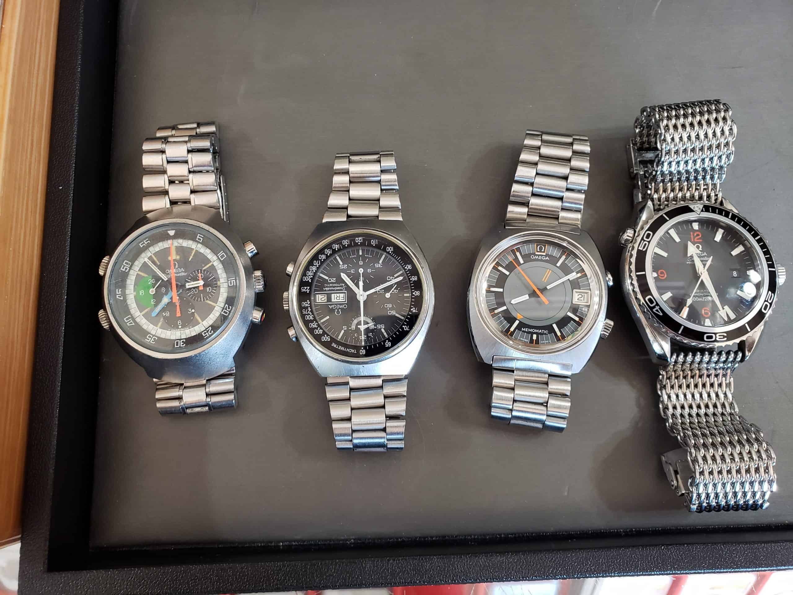 Four Omega watches on a tray: Flightmaster, Speedmaster, Memomatic and Planet Ocean, photographed at Apex Gold Silver Coins